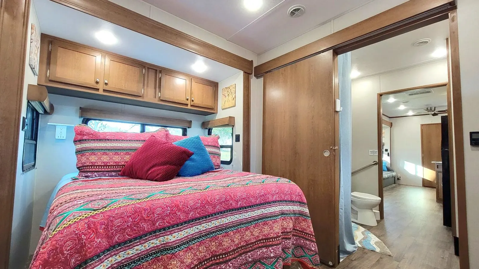 The comfy queen bed with pretty red patterned quilt and plenty of pillows.